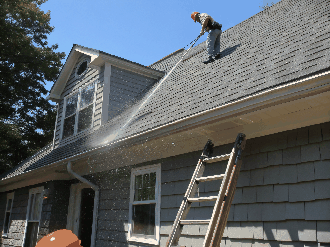 Soft wash cleaning applied gently to residential roof shingles and siding